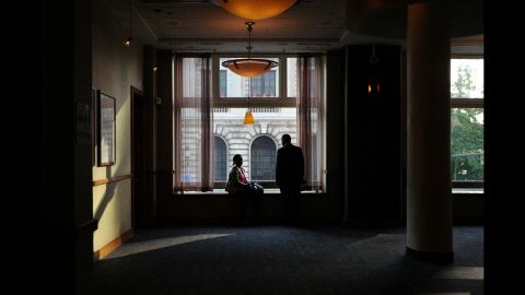 Two people take in the convention scene from a window in a bar. 