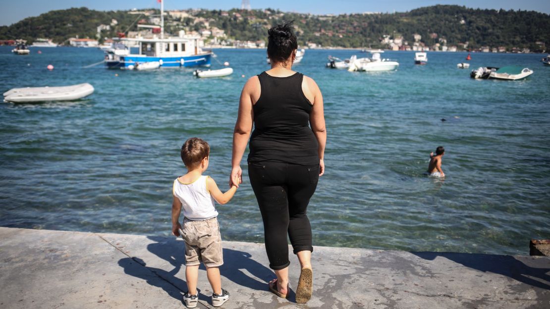 Damla, an unemployed high school dropout, hold's her son's hand as she poses for a photo next to the Bosphorous, in Istanbul. 