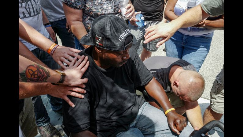 Members of a church group pray with a wheelchair-bound man and try to convince him that he will stand if he keeps praying with them.