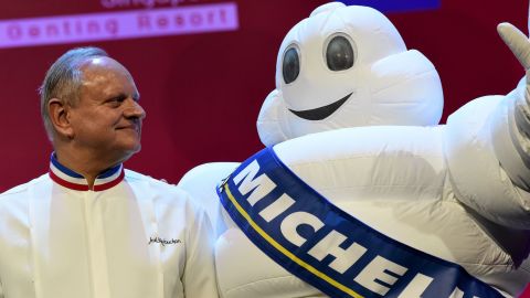 Joel Robuchon (L) whose eponymous restaurant was awarded three Michelin stars poses with the tyre company's mascot during the Michelin Guides Award ceremony in Singapore on July 21, 2016.
Culinary bible Michelin on July 21 awarded one star each to two street food hawkers in Singapore, the first in the guide's history. / AFP / ROSLAN RAHMAN        (Photo credit should read ROSLAN RAHMAN/AFP/Getty Images)