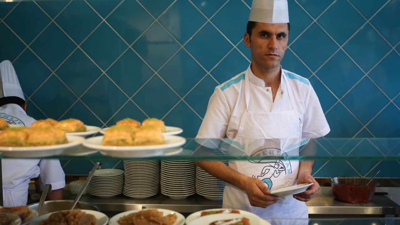 Ridvan, who works as a cook, helps a customer, in Istanbul.