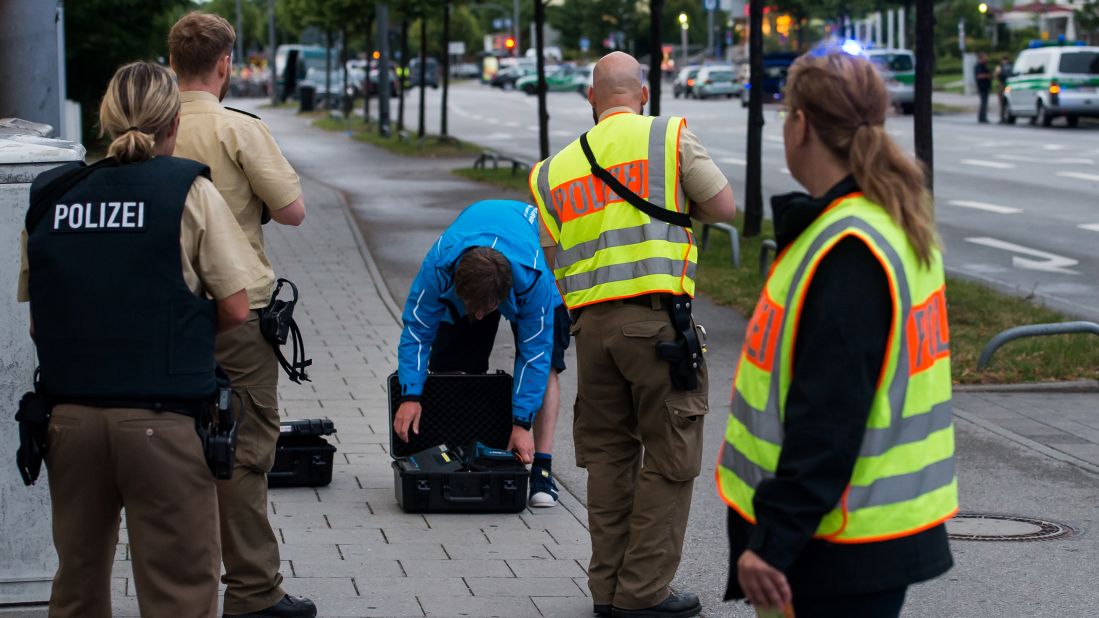 Police officers search a man outside the shopping mall where the shooting took place.