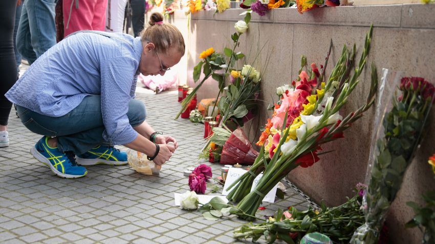 People lay flowers and candles outside the OEZ shopping center the day after a shooting spree left nine victims dead on Saturday, July 23 in Munich, Germany.