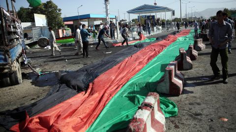 A banner in the colors of the Afghan flag is used to cover victim's blood after the deadly explosion.  