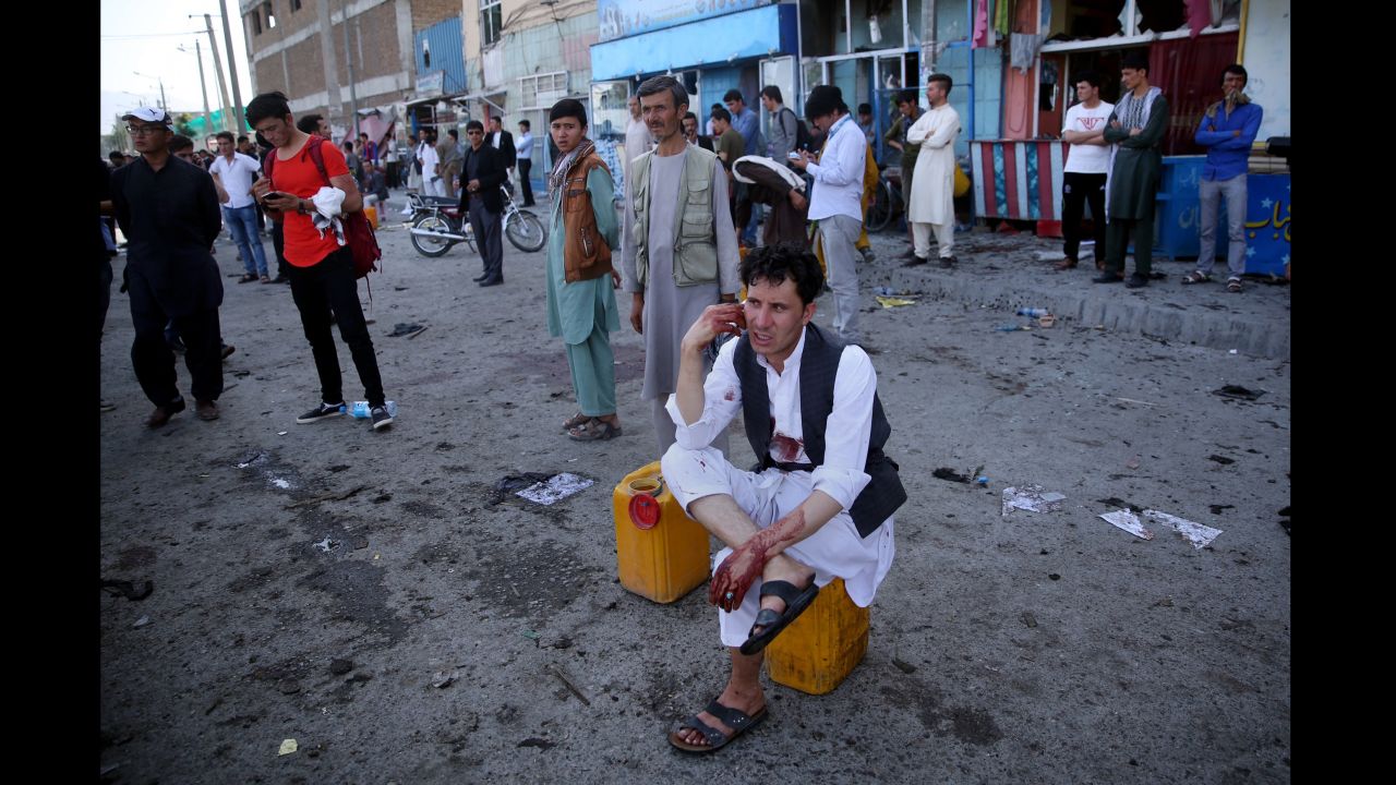 A bloodied man, who carried dead and wounded, speaks on the phone at the site of the suicide attack. 
