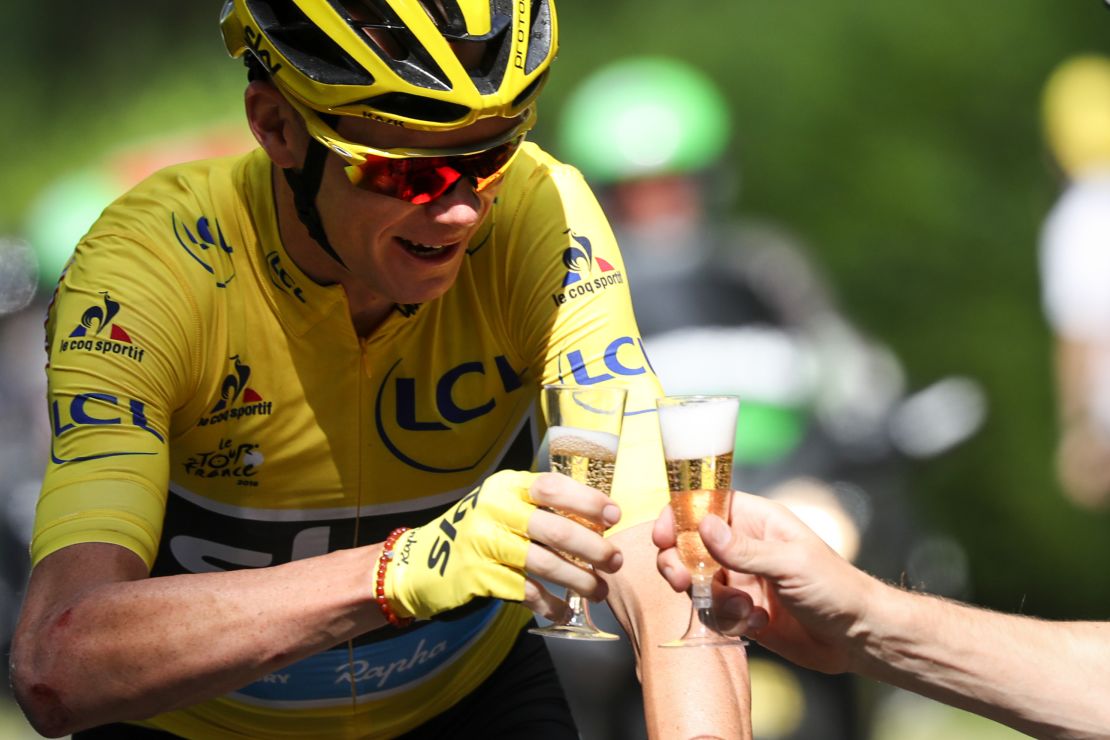Chris Froome drinks a glass of champagne as he rides at the start of the 113 km twenty-first and last stage of the 103rd edition of the Tour de France.