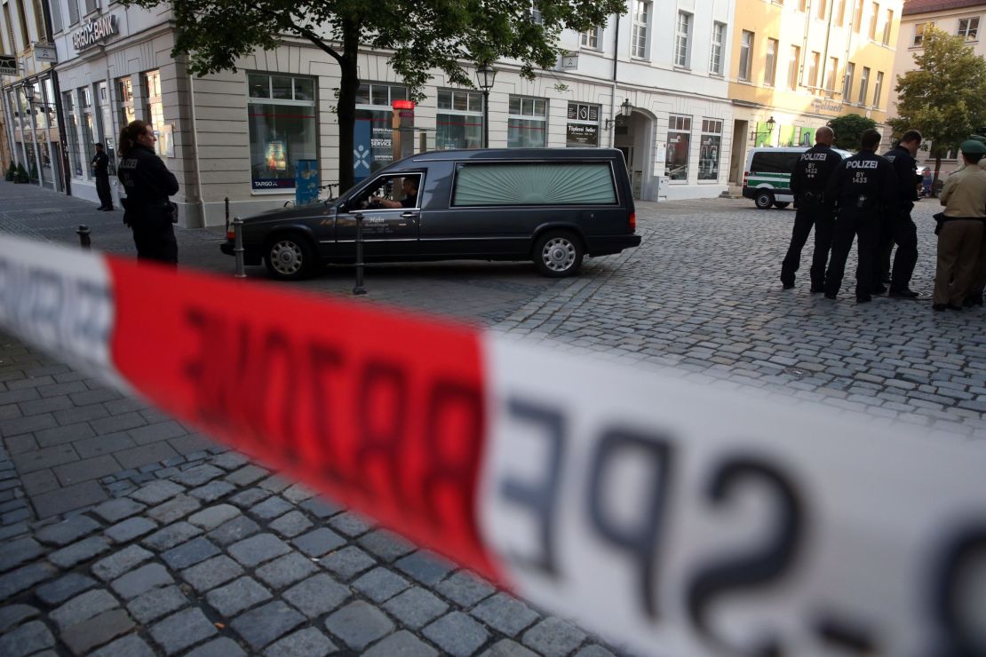 Police watch a hearse leave the scene of a suicide attack in the southern German city of Ansbach.
