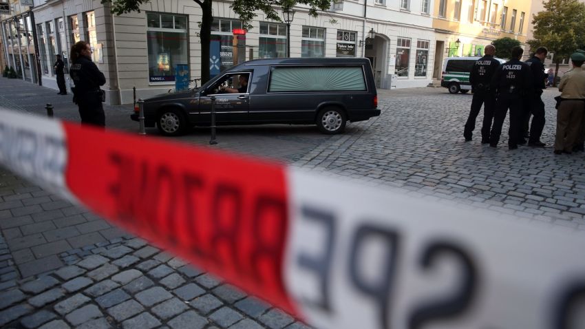 Police watch a hearse leave the scene of a suicide attack in the southern German city of Ansbach on 25 June, 2016 
A Syrian migrant set off an explosion at a bar in southern Germany that killed himself and wounded a dozen others late Sunday, authorities said, the third attack to hit Bavaria in a week.
The 27-year-old, who had spent a stint in a psychiatric facility, had intended to target a music festival in the city of Ansbach but was turned away because he did not have a ticket.
 / AFP / dpa AND DPA / Daniel Karmann / Germany OUT        (Photo credit should read DANIEL KARMANN/AFP/Getty Images)