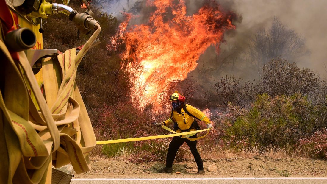 A fireman grabs his hose to battle a fire off Placerita Canyon Road in Santa Clarita.