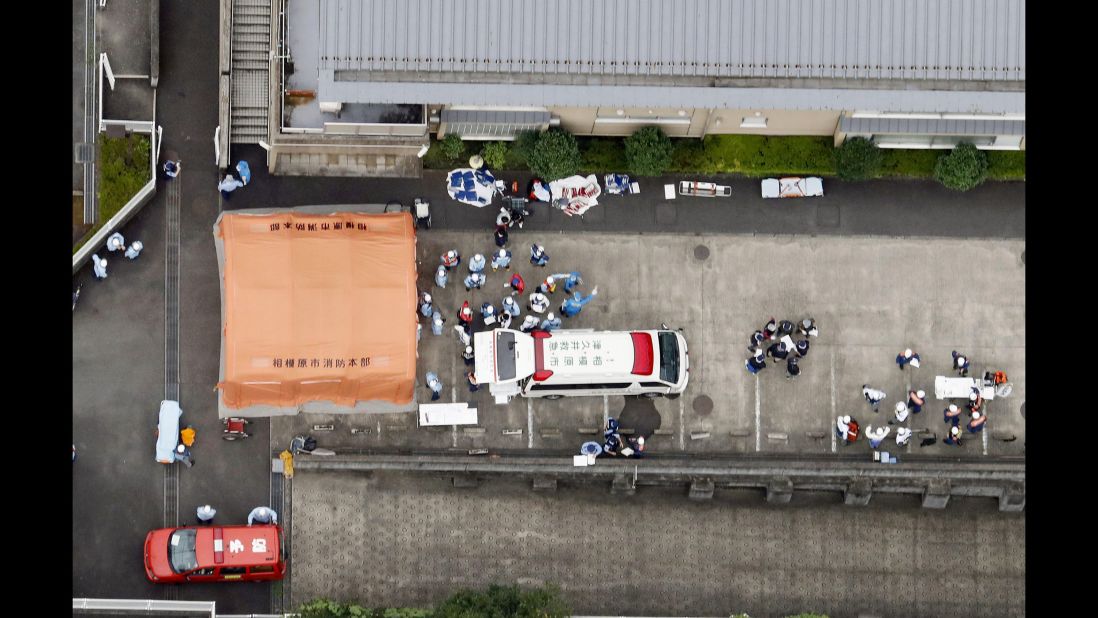 Ambulance crews are seen working outside the facility, now the site of one of Japan's deadliest mass killings since World War II.