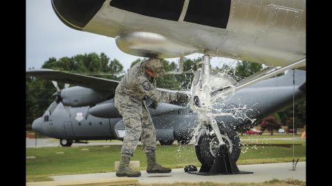 Air Force Master Sgt. Matthew Tabor breaks a bottle to christen an H-21B helicopter while wearing the "tiger-stripe" Airman Battle Uniform in July.