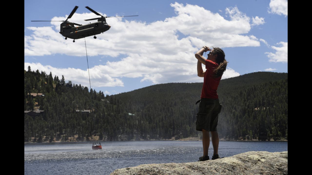 Adam Jones, a resident of Nederland, Colorado, takes pictures as an Army helicopter collects water from the Barker Dam to fight the Cold Springs Fire on Sunday, July 10.
