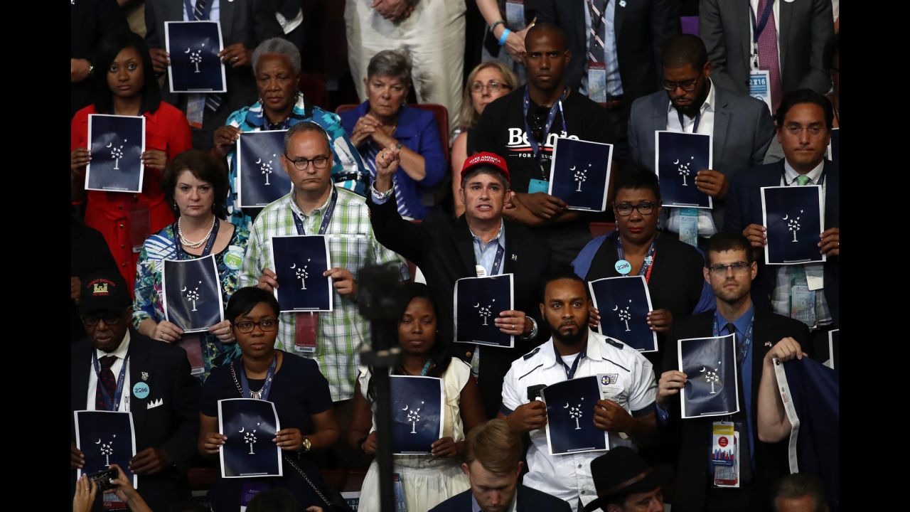 People hold up prints that pay respect to those who were killed in the Charleston, South Carolina, church shooting of June 2015. Two survivors of the shooting were speaking to the crowd.
