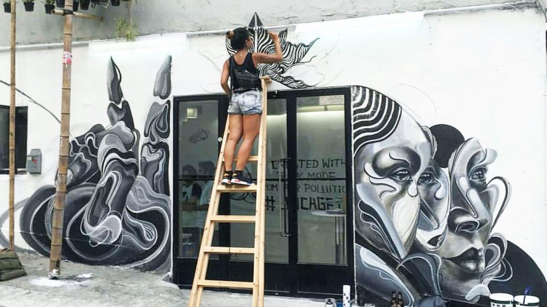 Artist Caratoes paints on a wall in with Air Ink