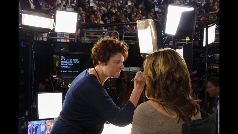 A woman has her makeup touched up before going on air.