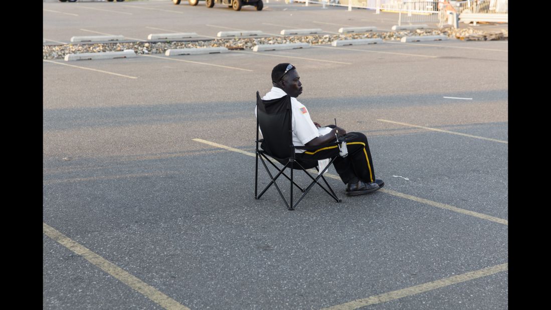 A security guard sits in a parking lot past the media entrance to the convention grounds.