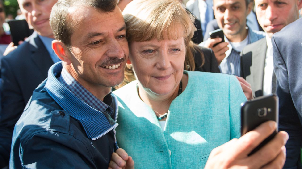 An asylum seeker takes a selfie with German Chancellor Angela Merkel during the leader's visit to refugee registration centre in Berlin on September 10, 2015.