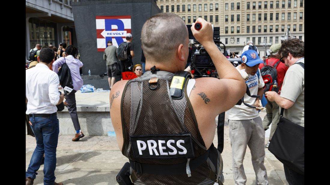 A member of the press films protesters outside City Hall.