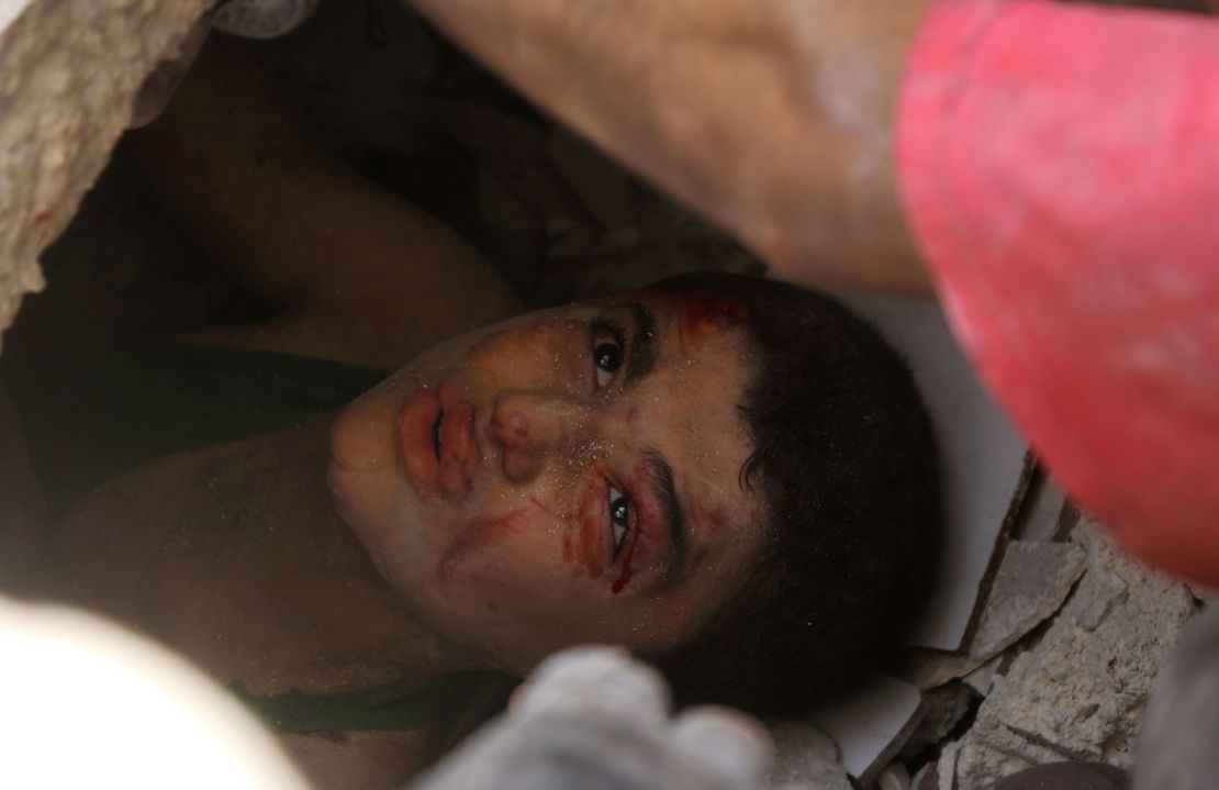 A Syrian boy trapped under the rubble of buildings destroyed following reported air strikes in Aleppo on July 25, 2016.