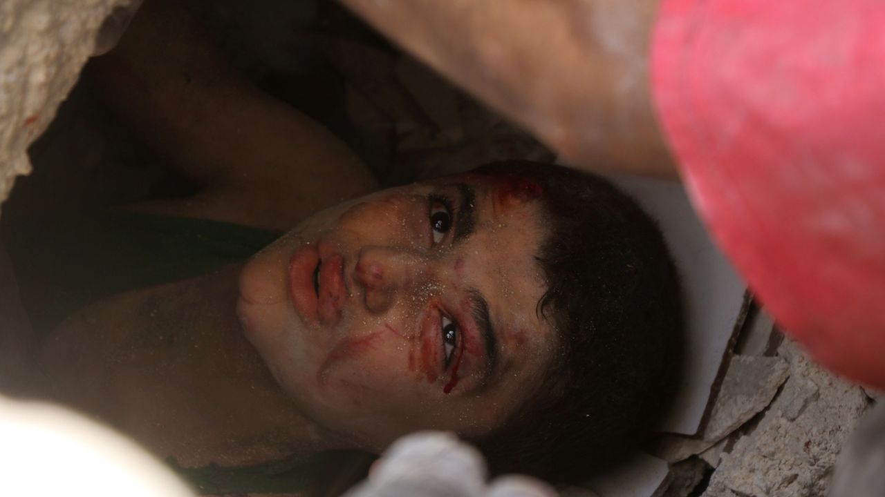A Syrian boy trapped under the rubble of buildings destroyed following reported air strikes in Aleppo on July 25, 2016.