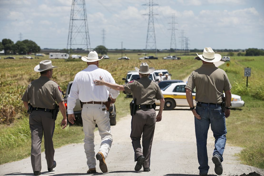Texas DPS Trooper Robbie Barrera, center right, puts her arm around Caldwell County Sheriff Daniel Law as he arrives on the scene of a hot air balloon crash Saturday. 