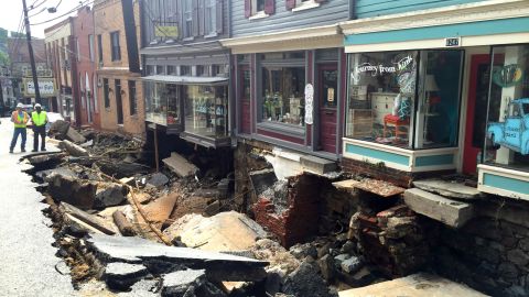 Workers gather on a street damaged by severe flooding in Ellicott City, Maryland.