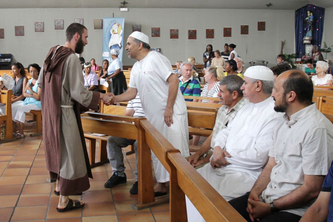 A Catholic monk welcomes Muslims to a mass in Nice, France, where people gathered to mourn a priest slain by jihadists.