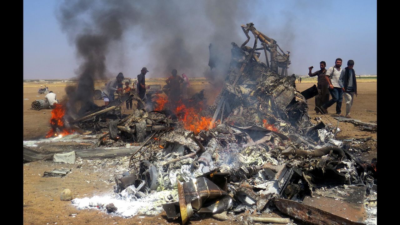 Syrians gather around the burning wreckage of a Russian chopper after it was shot down Monday.