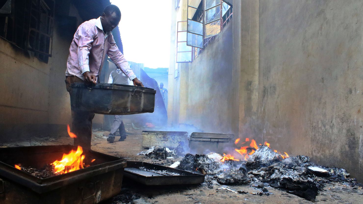 A student at a boys school in Kisii, Kenya, salvages personal effects from a smoldering dormitory building. 