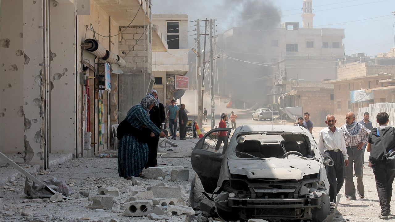 A woman inspects a damaged car after Russian planes carried out an airstrike over Etarib district of Aleppo, Syria.