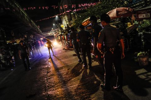 Police patrol a shanty community at night during curfew on June 8, 2016 in Manila.