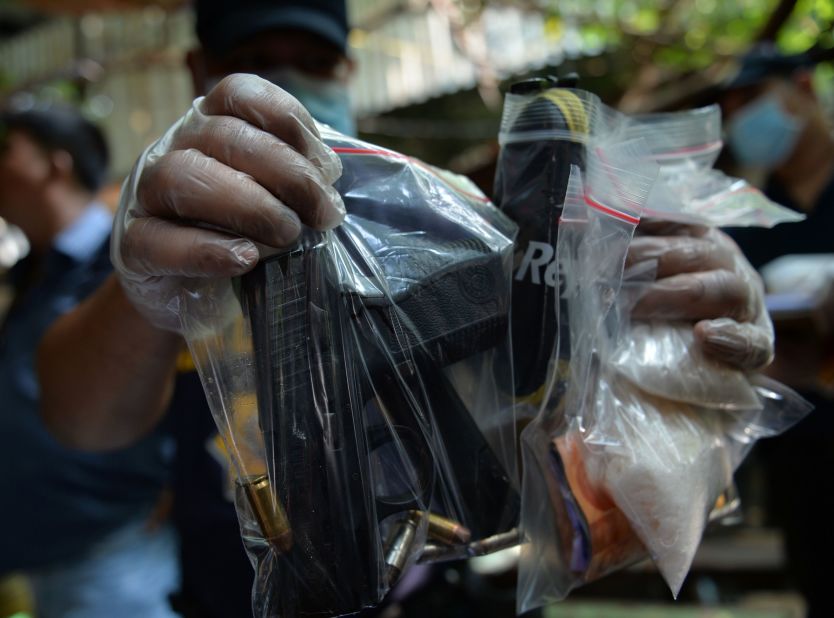 A Philippine police forensic investigator displays packets of drugs and a hand gun found inside a shanty where members of a suspected drug syndicate were killed after a shootout with police on July 3, 2016.