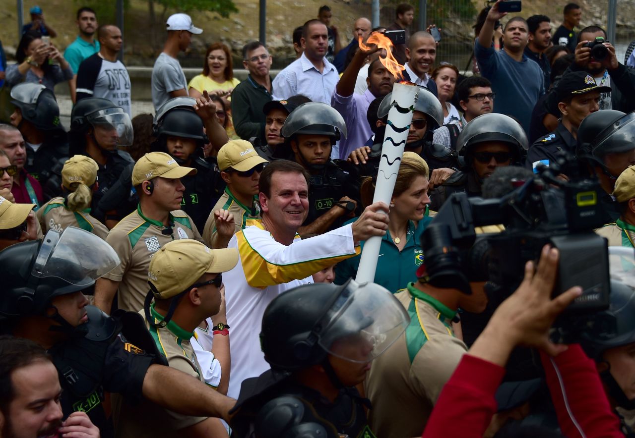 Rio mayor Eduardo Paes carries the Olympic torch after its arrival at the Naval Academy on Guanabara Bay, ahead of Friday's opening ceremony.