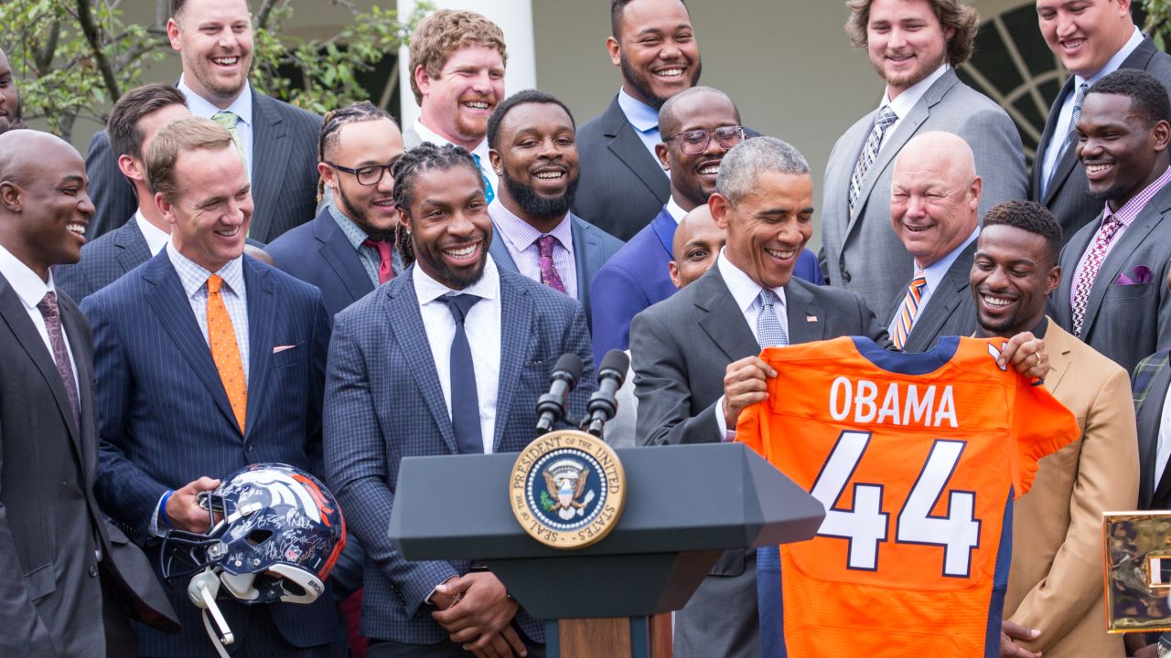 At June celebration President Barack Obama lifts a Denver Broncos jersey her received in honor of the team's Super Bowl 50 victory over Carolina Panthers.