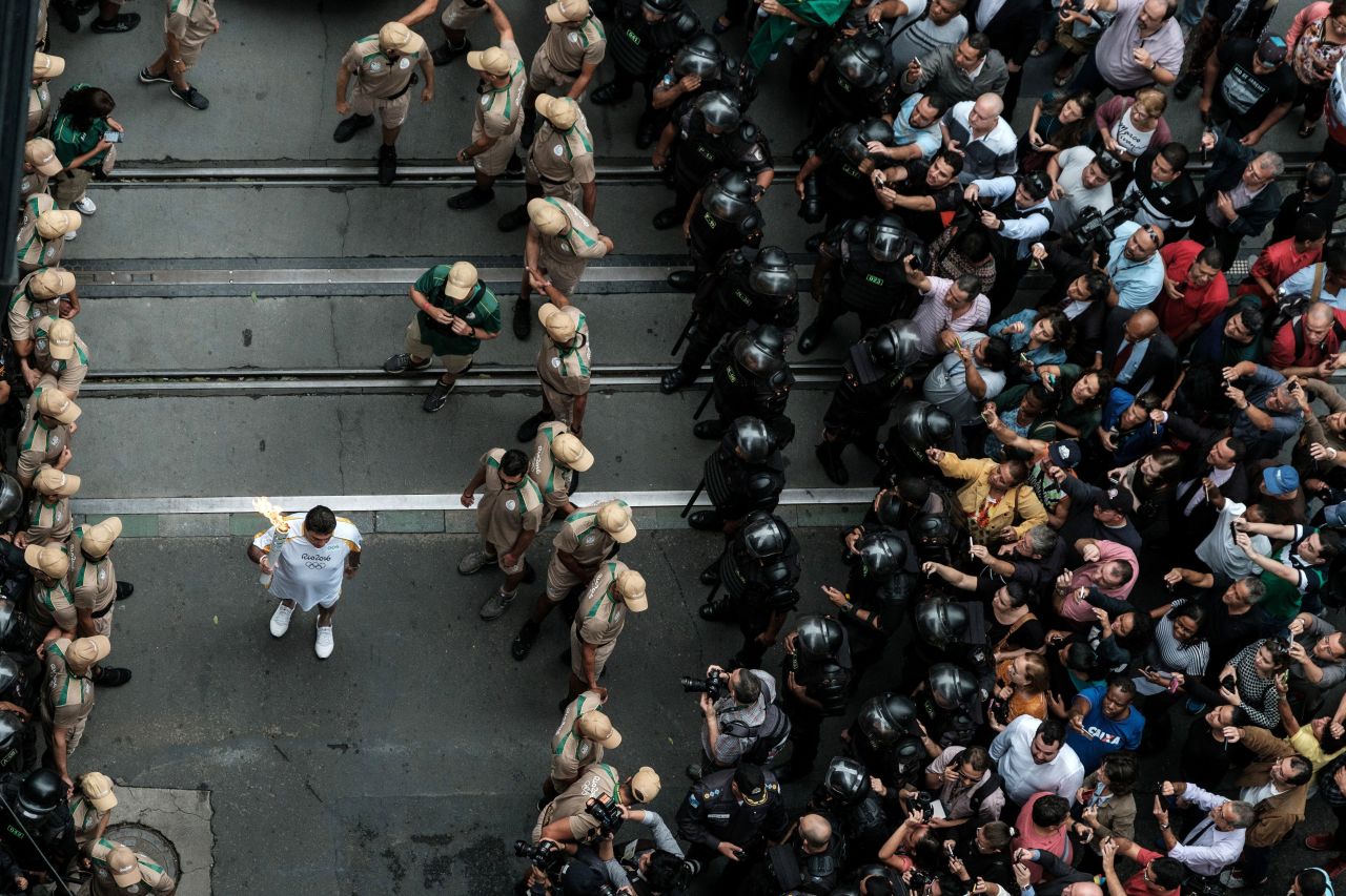 An Olympic torch bearer runs past the crowds held back by lines of security. National force police reportedly used tear gas and rubber bullets against protesters along the torch route Wednesday.