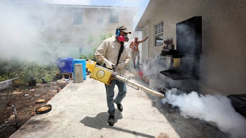 Carlos Varas, a Miami-Dade County mosquito inspector, sprays around homes in the Wynwood area of Miami.