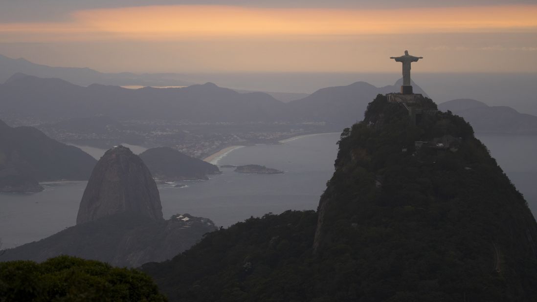 The sun rises over the Christ the Redeemer statue and Sugarloaf Mountain on August 4. 