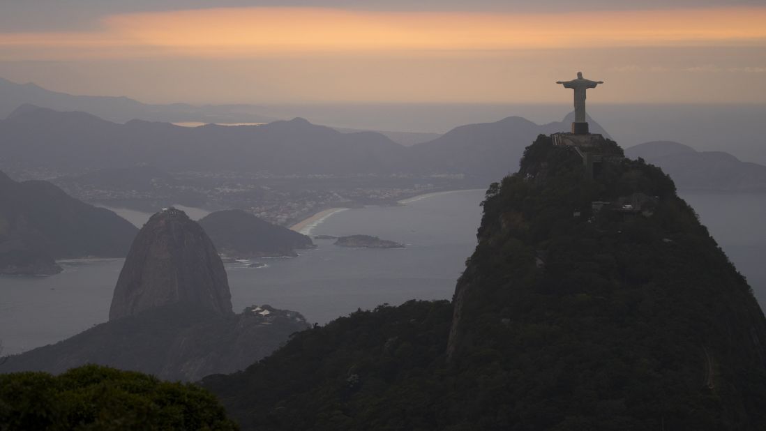 The sun rises over the Christ the Redeemer statue and Sugarloaf Mountain on August 4.