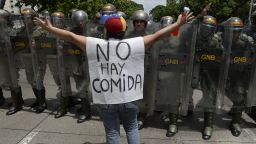 TOPSHOT - A woman with a sign reading "There is no food" protests against new emergency powers decreed this week by President Nicolas Maduro in front of a line of policemen in Caracas on May 18, 2016. 
Public outrage was expected to spill onto the streets of Venezuela Wednesday, with planned nationwide protests marking a new low point in Maduro's unpopular rule. / AFP / FEDERICO PARRA        (Photo credit should read FEDERICO PARRA/AFP/Getty Images)