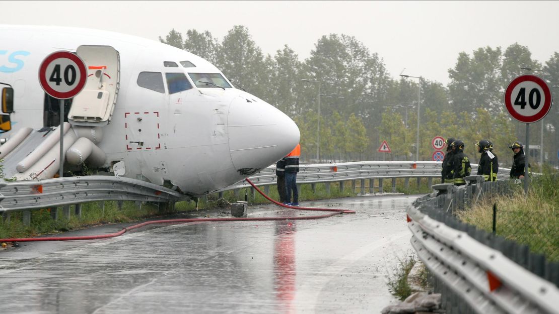 Firefighters work on a DHL cargo plane that skidded off a runway overnight at the airport of Bergamo Orio al Serio in northern Italy, crashing through a guard rail onto a highway on Friday, August 5.