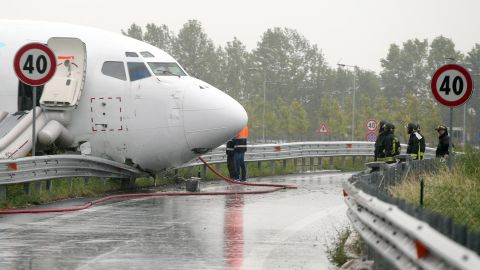 Firefighters work on a DHL cargo plane that skidded off a runway overnight at the airport of Bergamo Orio al Serio in northern Italy, crashing through a guard rail onto a highway on Friday, August 5.