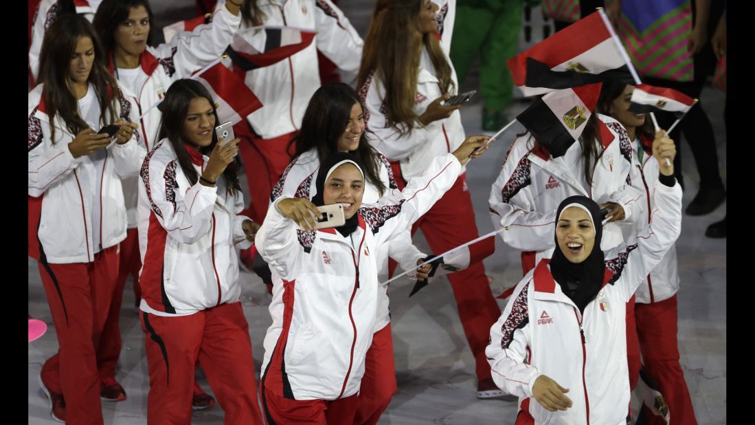 Egyptian athletes take photos as they march into the stadium.