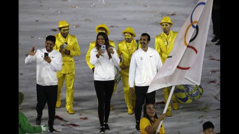 A volunteer carries the flag of the Independent Olympic Team.