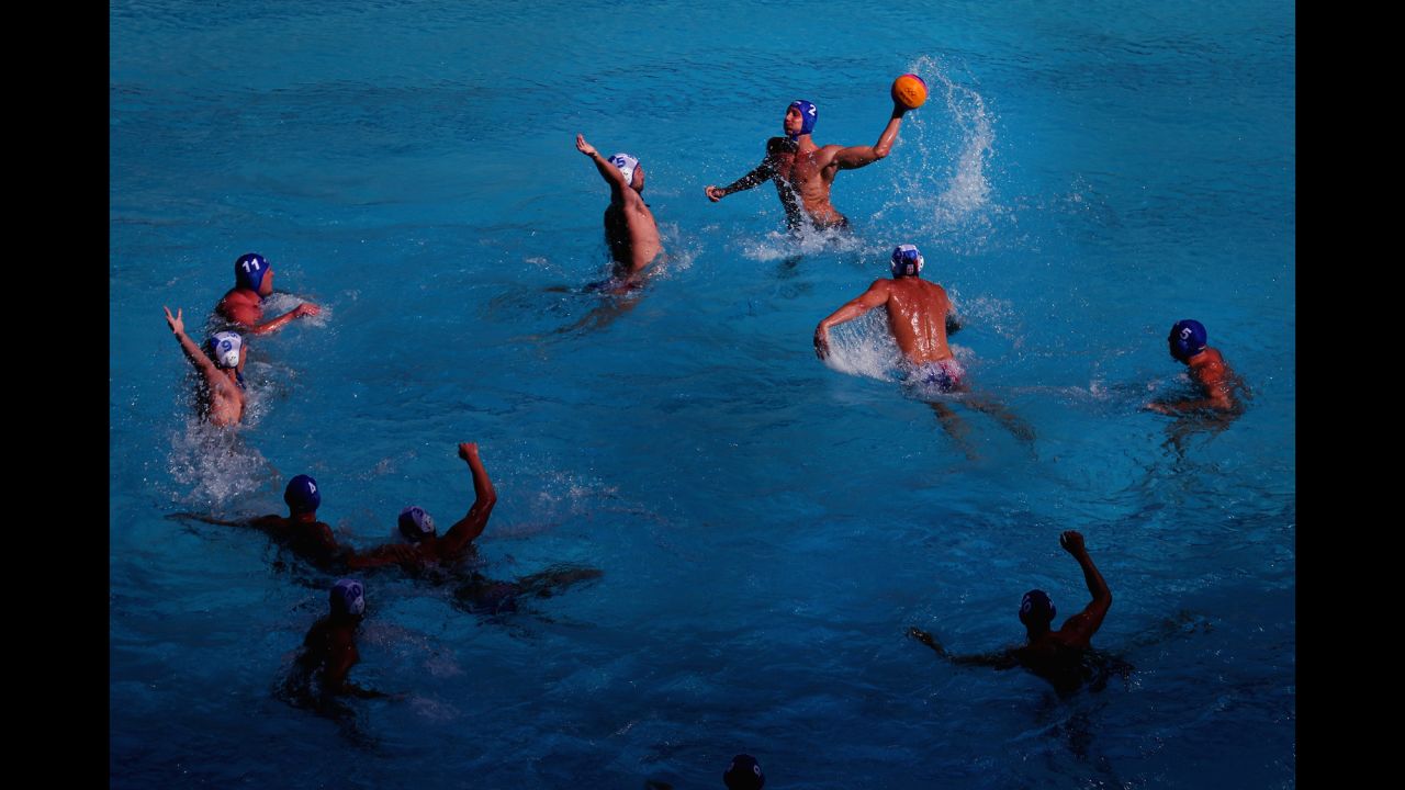 Hungary's Gergo Zalanki, top right, passes the ball against Serbia's Milos Cuk, top left, during the men's water polo preliminary round match between their two countries.