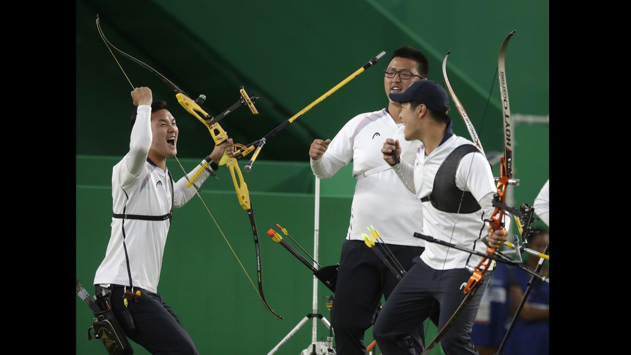 South Korea's Ku Bon-chan, Kim Woo-jin and Lee Seung-yun celebrate after winning the men's team archery gold medal match at the Sambadrome venue.