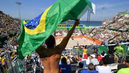 A man waves a Brazilian flag as he watches the women's beach volleyball qualifying match between Spain and Argentina at the Beach Volley Arena in Rio de Janeiro on August 6, 2016, for the Rio 2016 Olympic Games. / AFP / Leon NEAL        (Photo credit should read LEON NEAL/AFP/Getty Images)