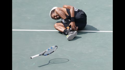 Dustin Brown of Germany grimaces after hurting his ankle during his match against Thomaz Bellucci of Brazil. Brown would later exit the game.
