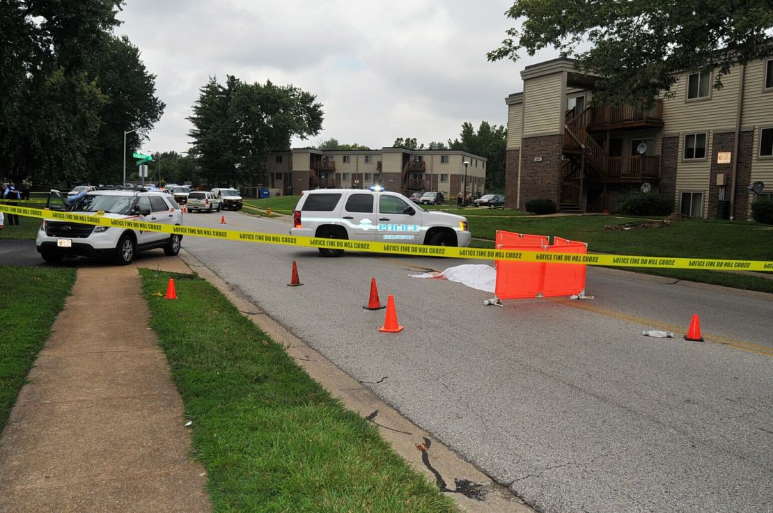 Michael Brown's covered body lies in the middle of Canfield Drive as Ferguson authorities investigate the scene on August 9, 2014.