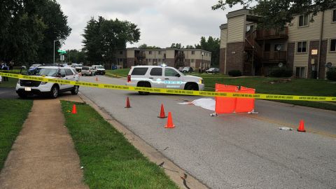 Michael Brown's covered body lies in the middle of Canfield Drive as Ferguson authorities investigate the scene on August 9, 2014.