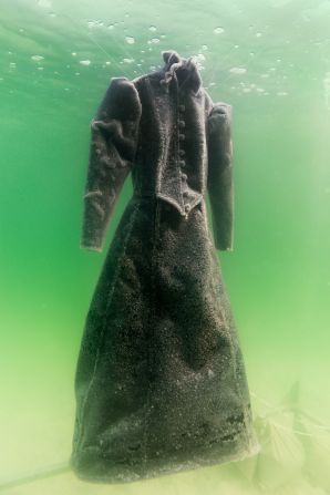 The black dress used is a replica of a traditional garment worn by the protagonist in "The Dybbuk," a traditional Yiddish play. In the play, the protagonist is a bride possessed by a demonic spirit, but Landau transforms the garment into a wedding dress by turning the black gown to white.